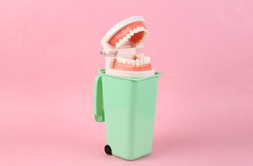 Plastic model of the jaw in trash can on pink background