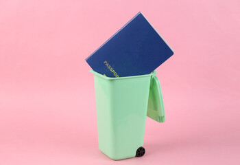 Passport in trash can on pink background