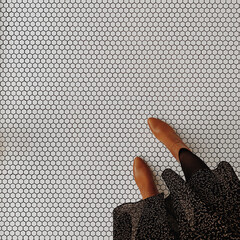 Female legs feet on white mosaic tile floor background. Minimal aesthetic fashion concept with...
