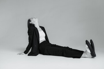 Fashion shot of stylish vogue woman in black suit sitting on floor in studio