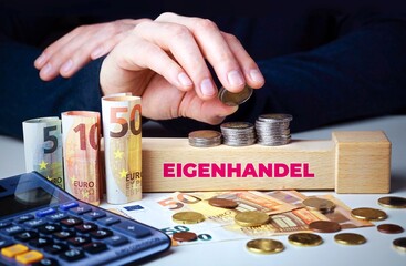 Eigenhandel. Hand baut Geldstapel auf einem Baustein mit Text. Turm aus Euro Münzen....