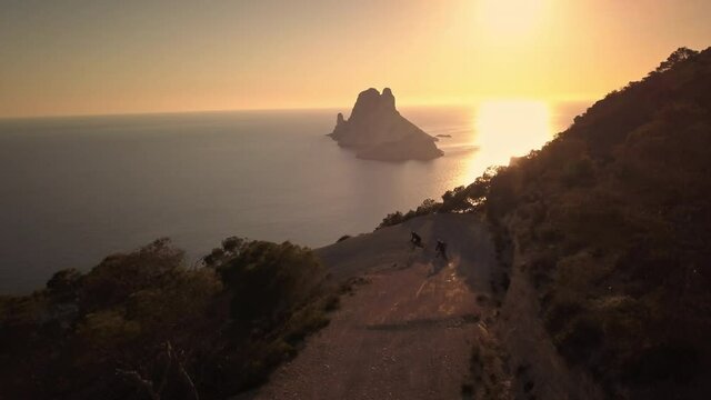 Extreme athletes ride epic Mountain bike trail, sunset, Es Vedra, Ibiza