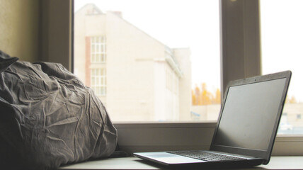 Laptop and pillow on the windowsill by the window