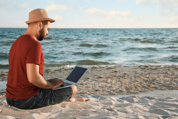 Man working with laptop on beach. Space for text