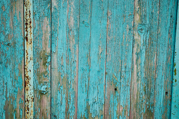 Fototapeta na wymiar An old wooden wall with peeling paint. Beautiful textured background.