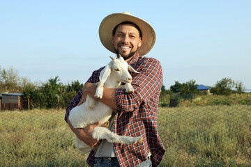 Fototapeta premium Man with goat at farm. Animal husbandry