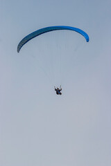 Paraglider flying in the blue sky