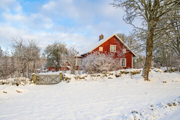 Red cottage with a gate in a beautiful  winter landscape
