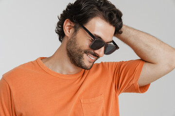 Young brunette man in sunglasses smiling and looking downward