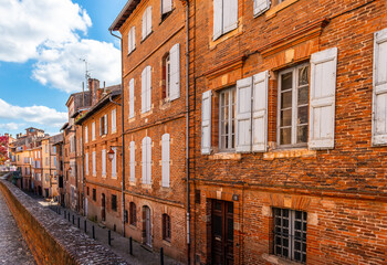 Fototapeta na wymiar Rue Caminade and its facades of old houses, facing the Sainte Cécile cathedral in Albi, in the Tarn region, in Occitanie, France