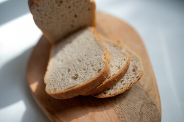 Round loaf of freshly baked sourdough bread with knife on cutting board, top view. Artisan bread with seeds on marble table. Rustic sourdough bread.