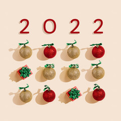 New Year 2022 holiday square flat lay, golden and red christmas balls and small gift box on pale pink Christmas minimal layout