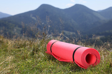 Rolled sleeping pad on grass in mountains, space for text