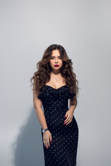 Beautiful girl brunette in a little black dress with red lipstick