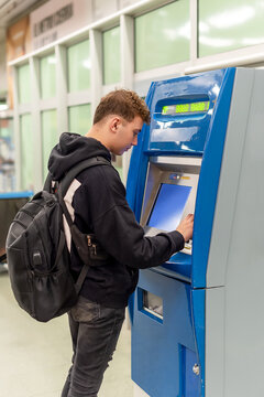 Young man with a backpage buying tickets from a vending machine in a subway station
