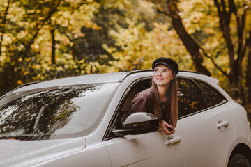  Woman with long hair in black hat and brown shirt looking out from white car