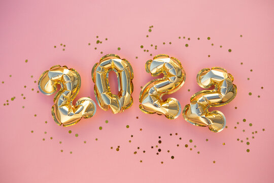Happy New year 2022 celebration. Bright gold balloons figures, New Year Balloons with glitter stars on pink background. Christmas celebration. Gift card - Powered by Adobe