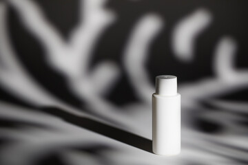 Blank white plastic bottle of cosmetic product on table against shadows space for design