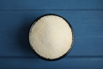 Gelatin powder in bowl on blue wooden table, top view