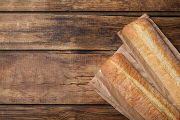 Fresh tasty baguettes on wooden table, flat lay. Space for text