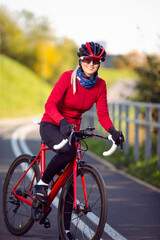 Professional Road Cycling. Caucasian Female Cyclist With Road Bike Posing Outdoors Against Autumn Background