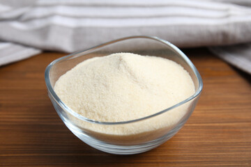 Gelatin powder in glass bowl on wooden table, closeup