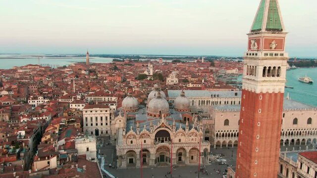 Scenic Aerial View of Main Landmark in Venice, Italy - Piazza San Marco with St Mark's Basilica and Campanile with Adriatic Sea at background. Popular Touristic City Destination. 4K Zoom out shot 