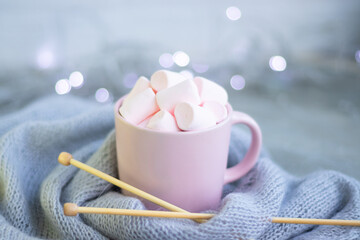 knitting needles, a cup of coffee with pink marshmallows.Christmas lights.
