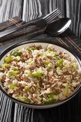 Dirty rice is a classic Cajun dish that is typically made with chicken livers and ground meat close-up in a plate on the table. Vertical