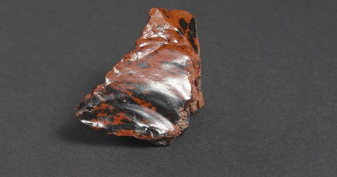 Obsidian mahogany. Igneous rock. Rotation on a dark background.