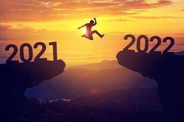 Silhouette man jump between 2021 and 2022 years with sunset background, Success new year concept.