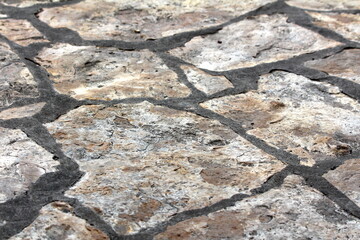 Traditional natural stone tiles sidewalk made from various size rocks held together with concrete...