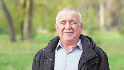 Senior man with a mustache in the park. portrait of a gray-haired man in a shirt and black jacket.