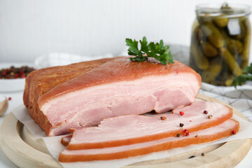 Delicious smoked bacon with parsley and peppercorns on wooden plate, closeup