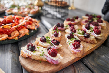 Delicious canapes with camembert and blackberries. Tasty buffet table. Summer party. Catering concept