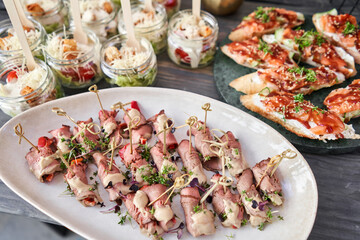 Delicious canapes with pork ham with dried tomatoes. Tasty buffet table. Summer party. Catering concept