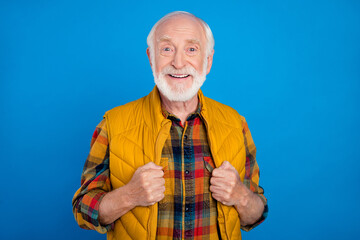 Portrait of attractive cheerful grey-haired man wearing cosy seasonal clothes isolated over bright blue color background