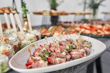 Delicious canapes with pork ham with dried tomatoes. Tasty buffet table. Summer party. Catering concept
