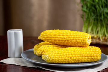 Sweet hot boiled corn on grey plate with salt