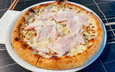 Close-up on a restaurant table pizza with prosciutto cotto and taleggio cheese