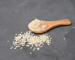 close up of sesame flour and sesame seeds in a wooden spoon. alternative type of flour. gluten free product. flour for dieting and low carb healthy meal.