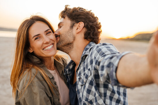 White young couple kissing and hugging while taking selfie photo