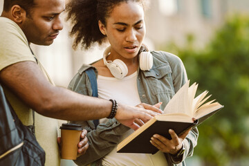 Multiracial young students reading and discussing book together