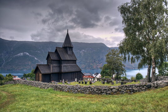 Alte Stabkirche aus Holz in Urnes, Norwegen über Fjord mit Friedhofsmauer