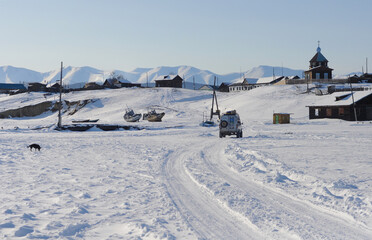 Baikal lake, winter ice road to small fishermen village. Blue landscape with car and boats. 