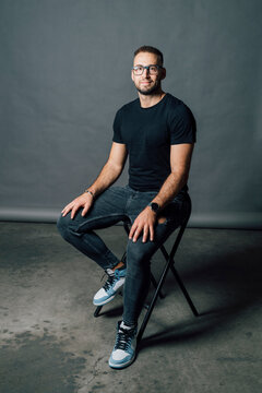 Mid adult man wearing eyeglasses sitting on chair in studio
