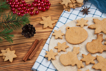 full plate of homemade freshly made gingerbread cookies on wooden background. Christmas tree decorations on the table. Classic traditional Christmas cookies with spices, cinnamon, cumin and ginger