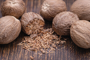 Pile of nutmegs on a wooden brown background. Close-up, studio shot.