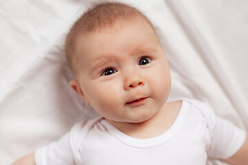 portrait of a cute smiling newborn baby in a white bodysuit on a white background close up. products for children. concept of happy childhood and motherhood. child care. High quality photo