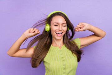 Photo of cheerful positive lady good mood enjoy listen music headset wind blow hair isolated on violet color background